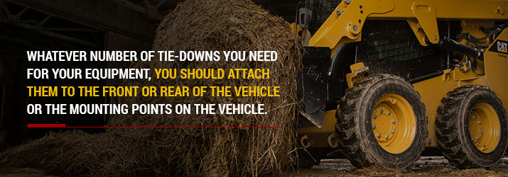 Loader lifts hay bale in barn.