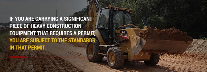Backhoe loader transporting a large bucket of dirt.